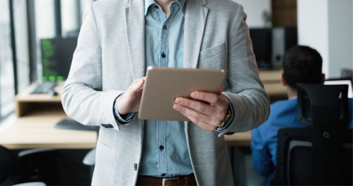 hombre de traje sosteniendo tablet mirando marketing de contenidos en ella