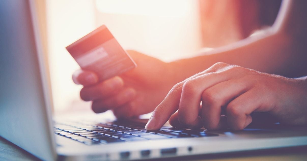 hombre mirando marketing de contenido en computadora y comprando online con tarjeta de crédito