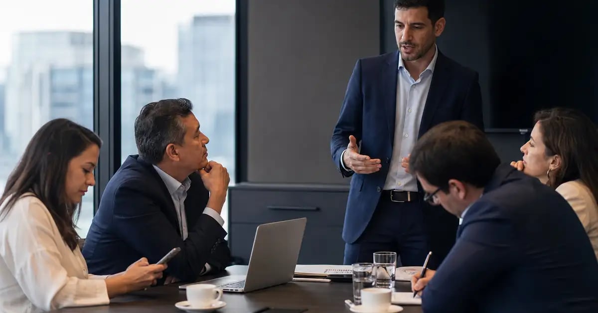 Comité de compra B2B latinoamericano en una sala de juntas, con una persona presentando y cuatro escuchando con distinto grado de interés